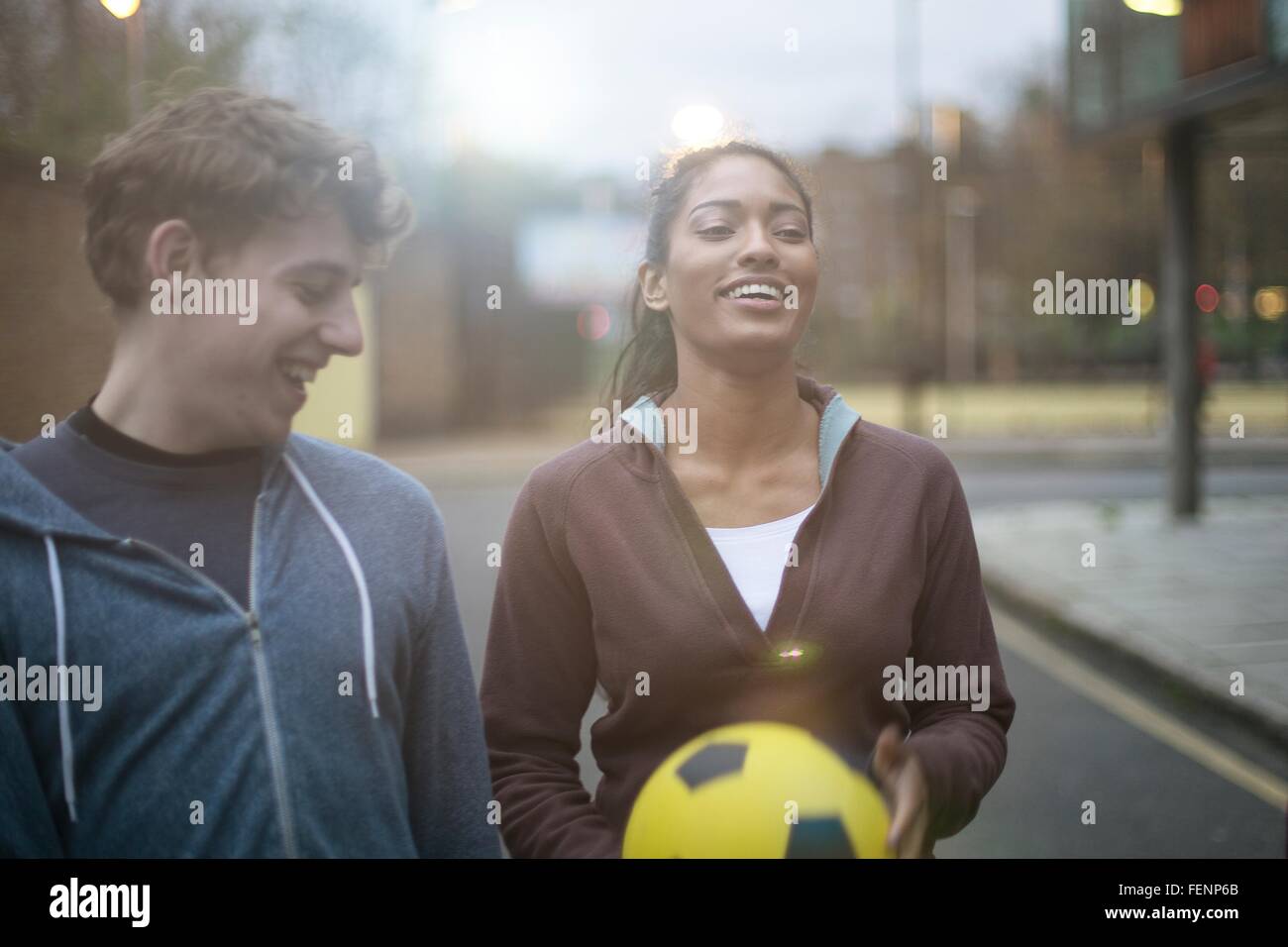 Junger Mann und Frau in der Straße wandern, halten Fußball Stockfoto