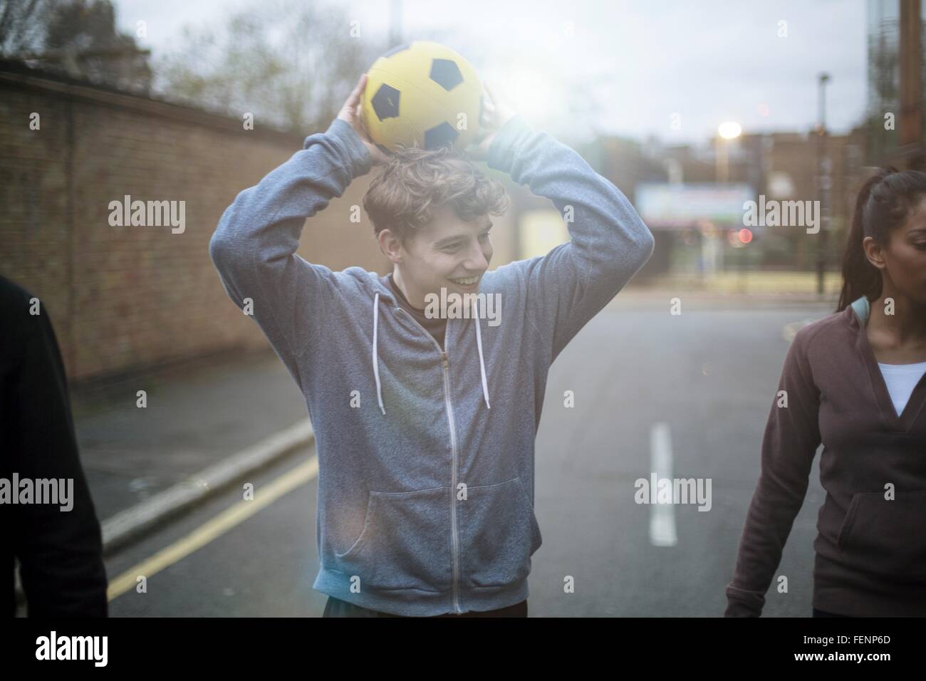 Gruppe von Erwachsenen die walking Street, Holding-Fußball Stockfoto