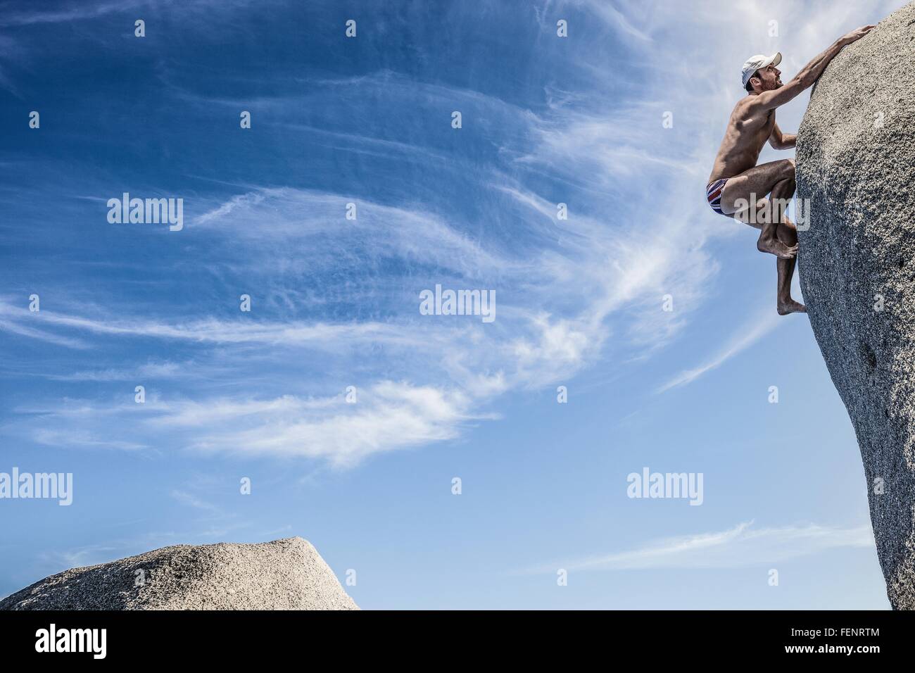 Mann trägt Badehose Klettern Fels, Villasimius, Sardinien, Italien Stockfoto
