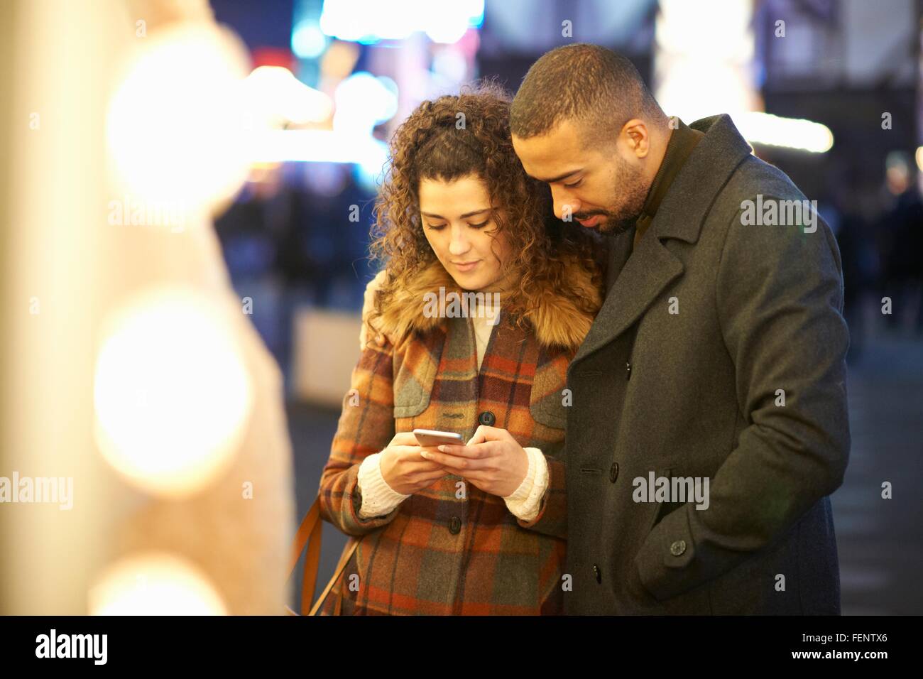 Paar auf der Suche auf Smartphone, im Freien, in der Nacht Stockfoto