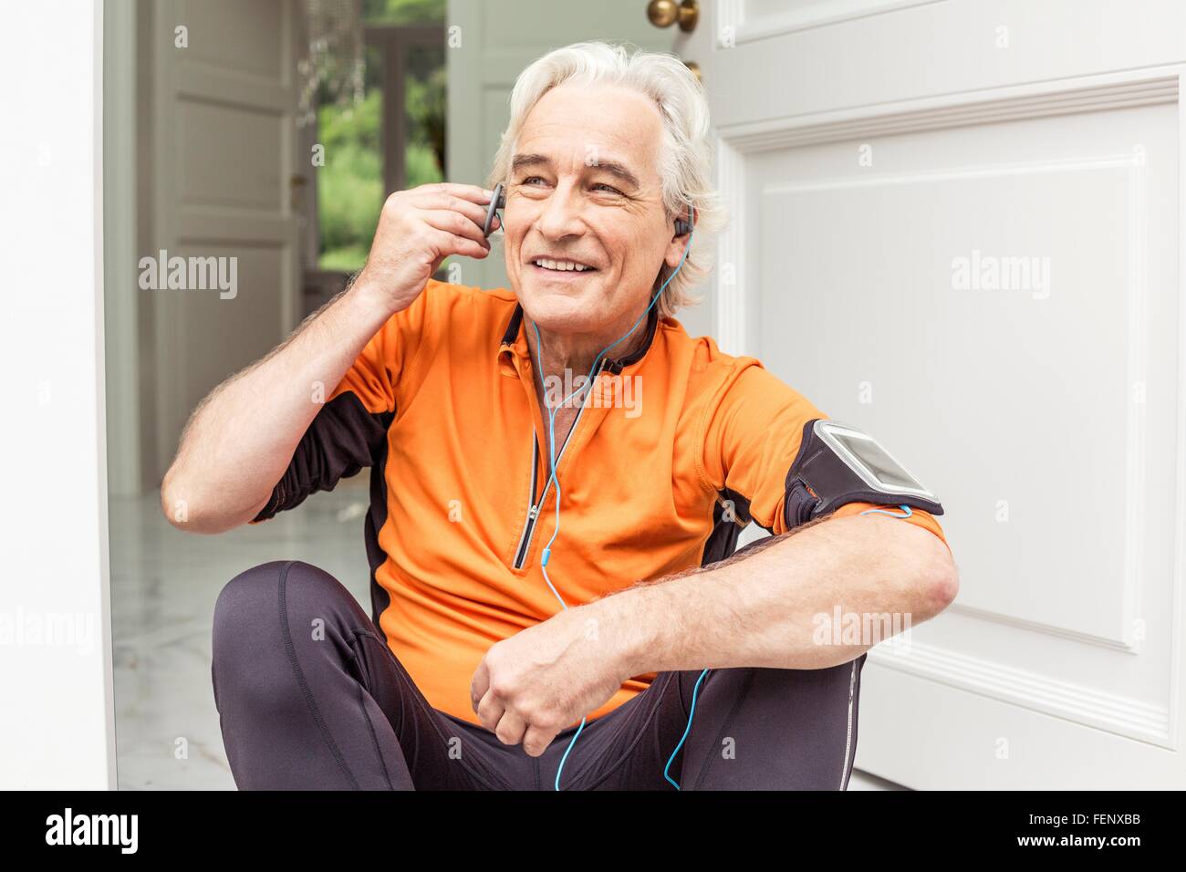 Ältere männliche Läufer an Haustür Kopfhörer Musik wird vorbereitet Stockfoto