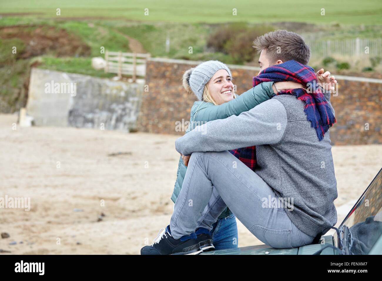 Romantische junges Paar auf Motorhaube am Strand sitzen Stockfoto