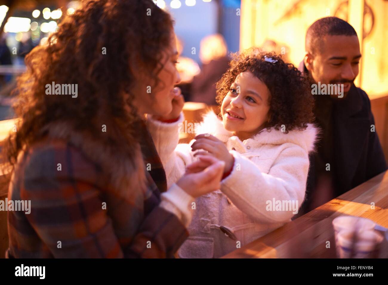 Mädchen im Freizeitpark mit Eltern lächelnd am Tisch sitzen Stockfoto
