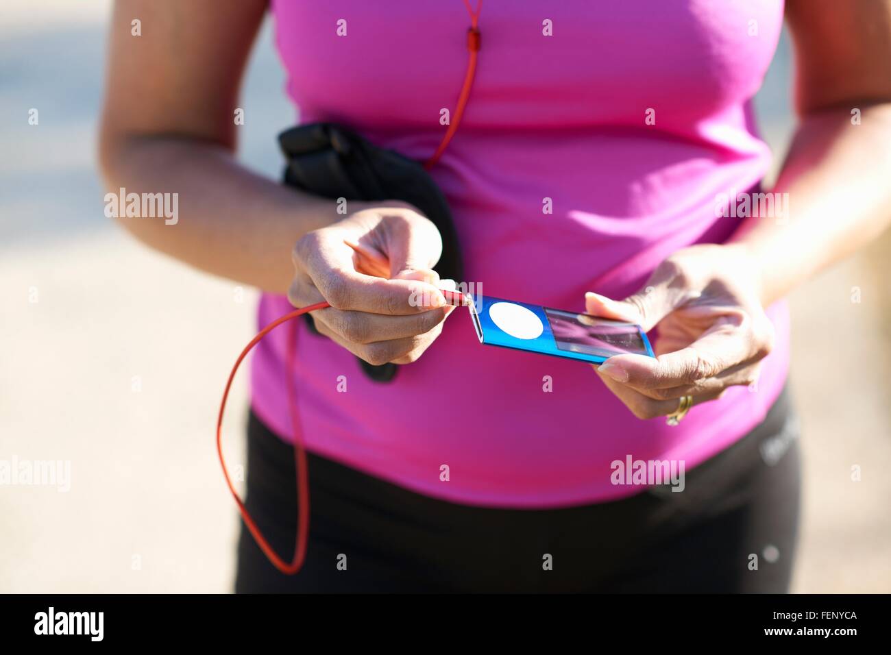 Mittleren Bereich der Reife Frau einstecken Audiobuchse beschnitten in MP3-player Stockfoto