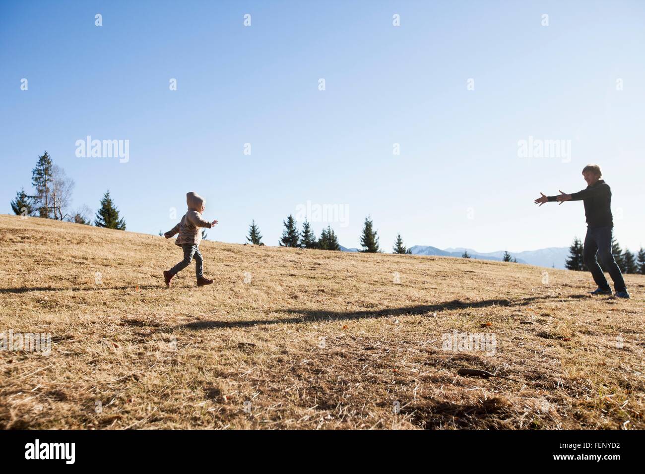 Weiblichen Kleinkind laufen Vater auf Hügel, Tegernsee, Bayern, Deutschland Stockfoto