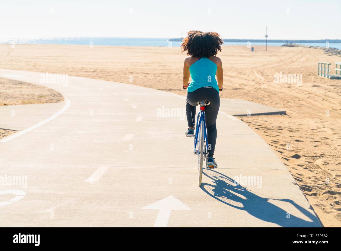 Mitte erwachsenen Frau Radfahren auf Weg am Strand Rückansicht Stockfoto
