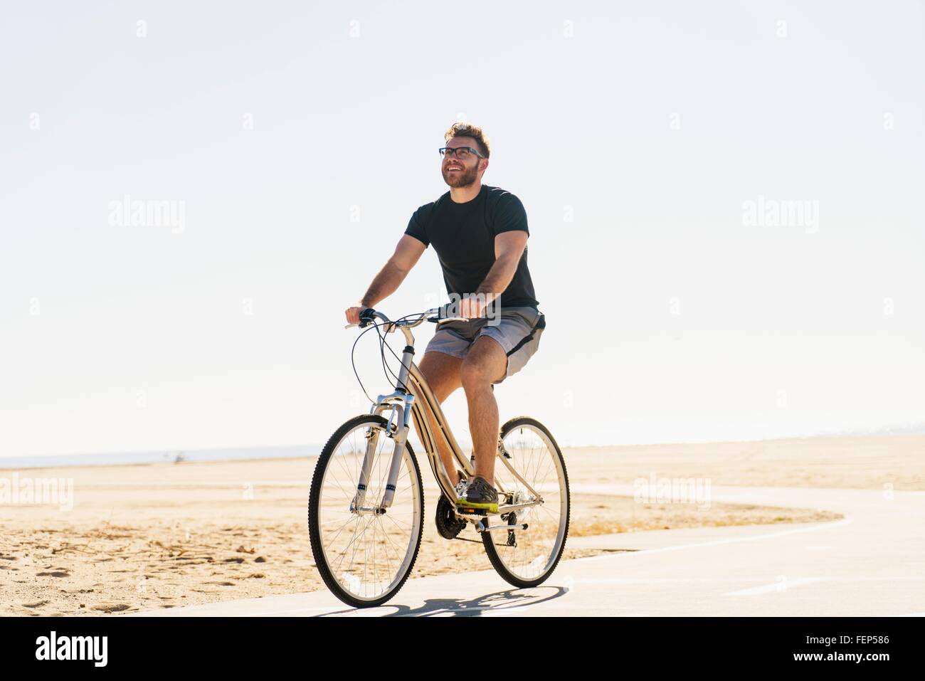 Junger Mann Radfahren entlang Weg am Strand Stockfoto