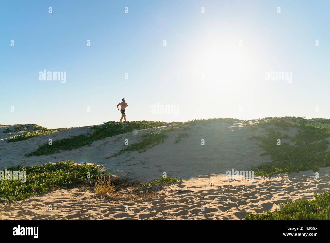 Junger Mann läuft entlang der Sanddünen Stockfoto