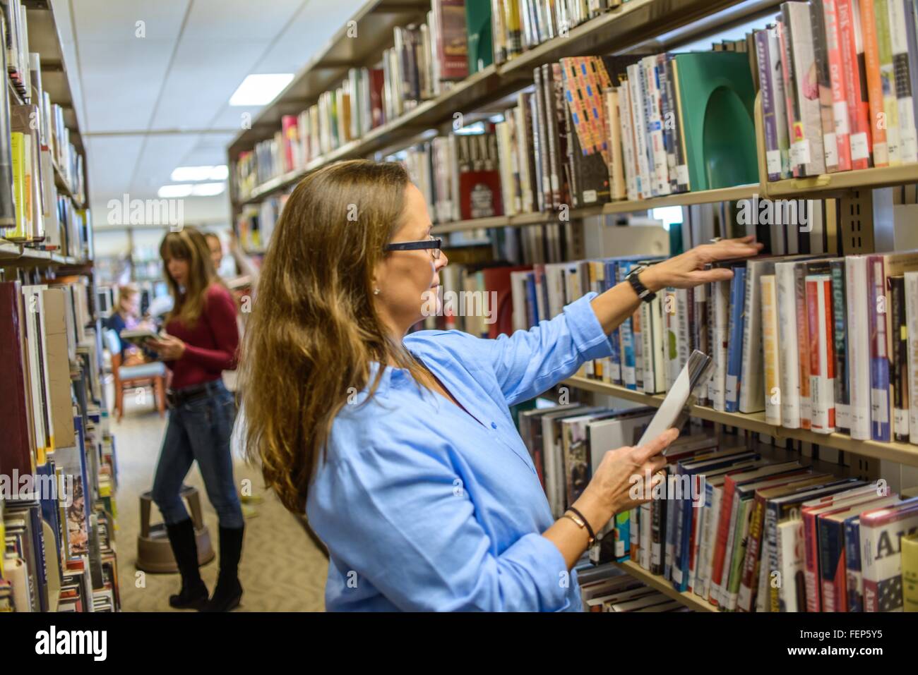 Reife Frau, die Auswahl der Bücher in der Bibliothek Stockfoto
