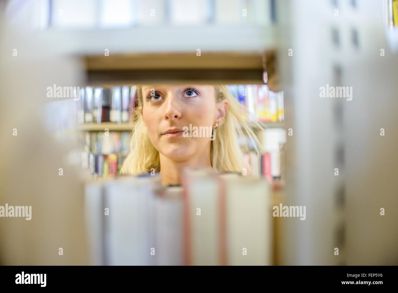 Nahaufnahme von junge Frau hinter Bücherregalen in Bibliothek Stockfoto