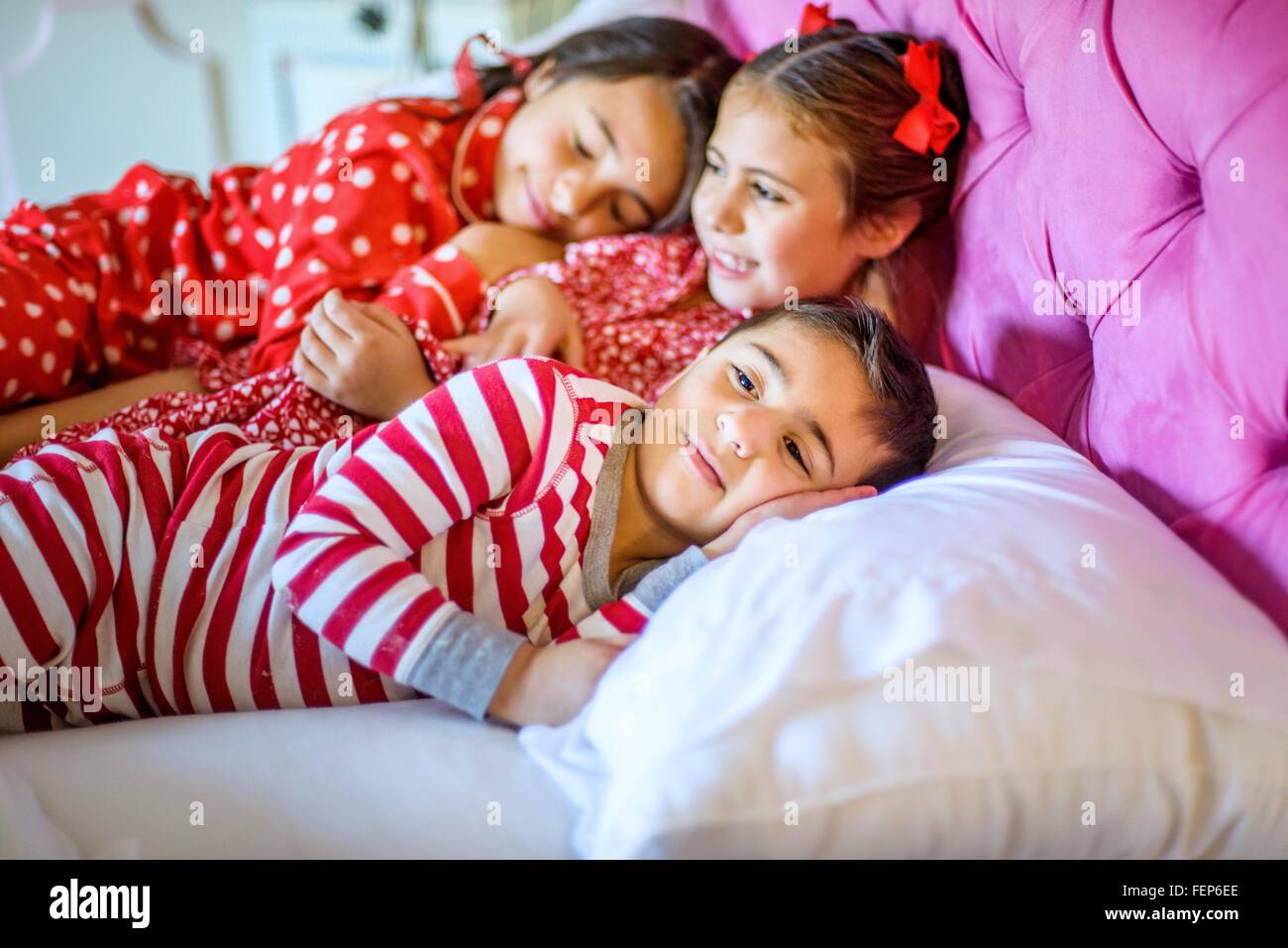 Süsser Boy und zwei Schwestern im Bett liegend Stockfoto