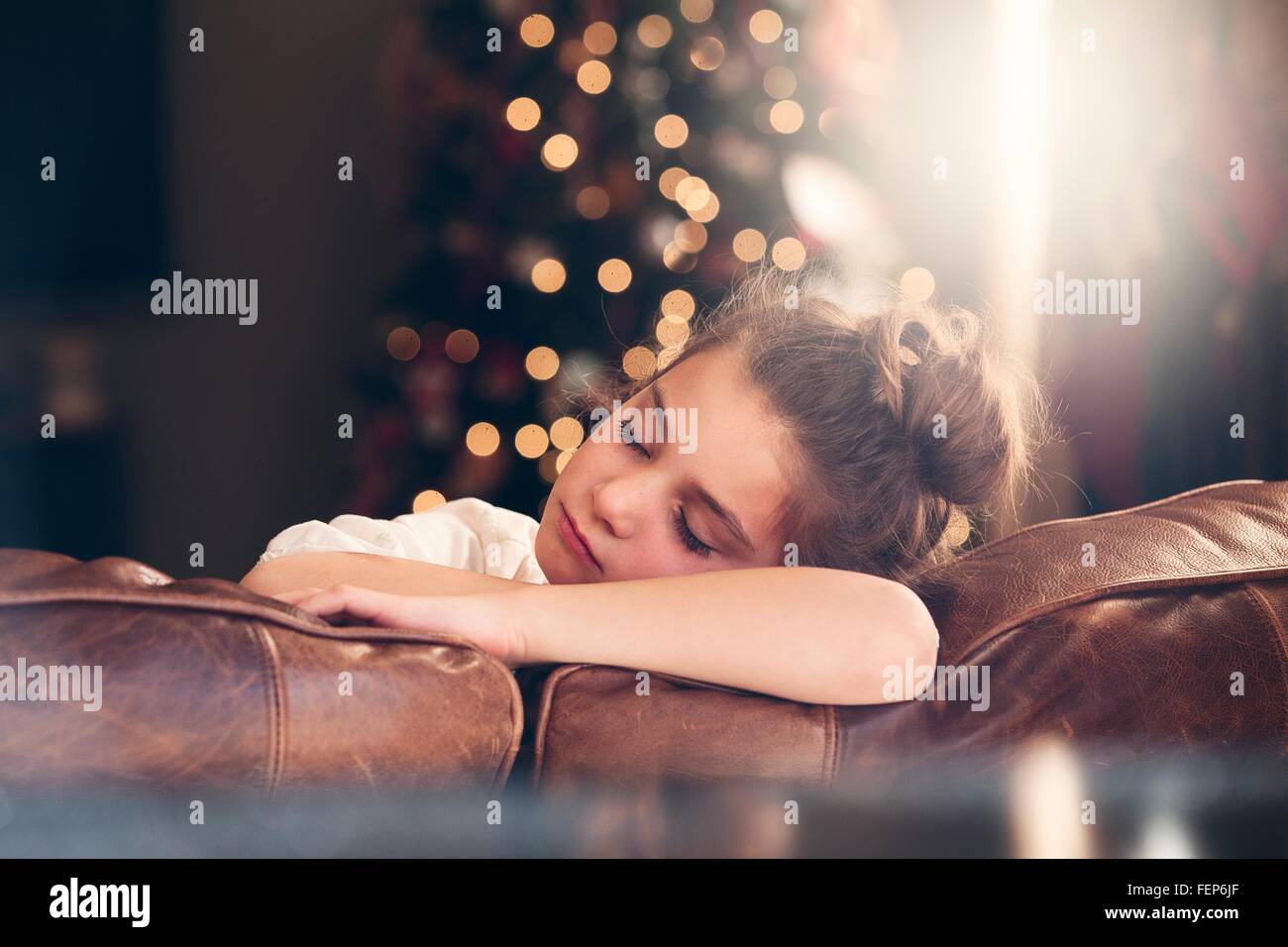 Porträt von Mädchen schläft auf dem Sofa vor Weihnachtsbaum Stockfoto