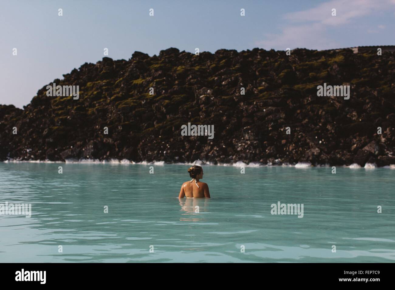 Rückansicht der Mitte Erwachsene Frau Taille tief im Wasser, Thermalquellen in Blue Lagoon Island Stockfoto