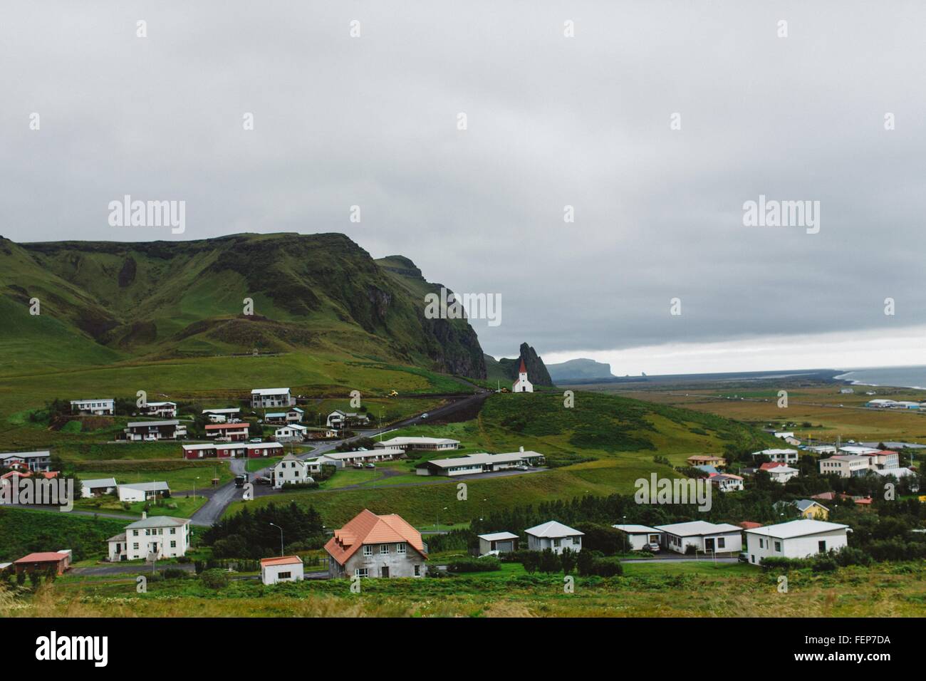 Vogelperspektive Blick auf Dorf an der Küste von üppigen grünen Berg, Vik, Island Stockfoto