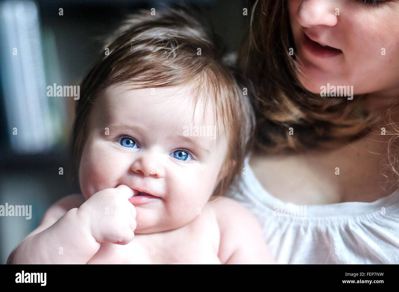 Mutter hält Tochter mit Finger im Mund, Blick auf die Kamera zu Lächeln Stockfoto