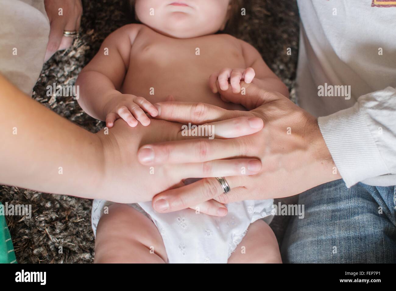 Zugeschnittenen Draufsicht der Mutter und Väter Hand auf Baby Mädchen Bauch Stockfoto
