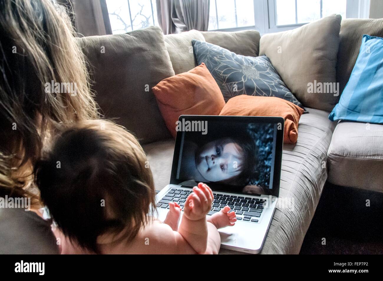 Über Schulter Blick der Mutter auf Sofa Blick auf Fotos von Tochter auf laptop Stockfoto