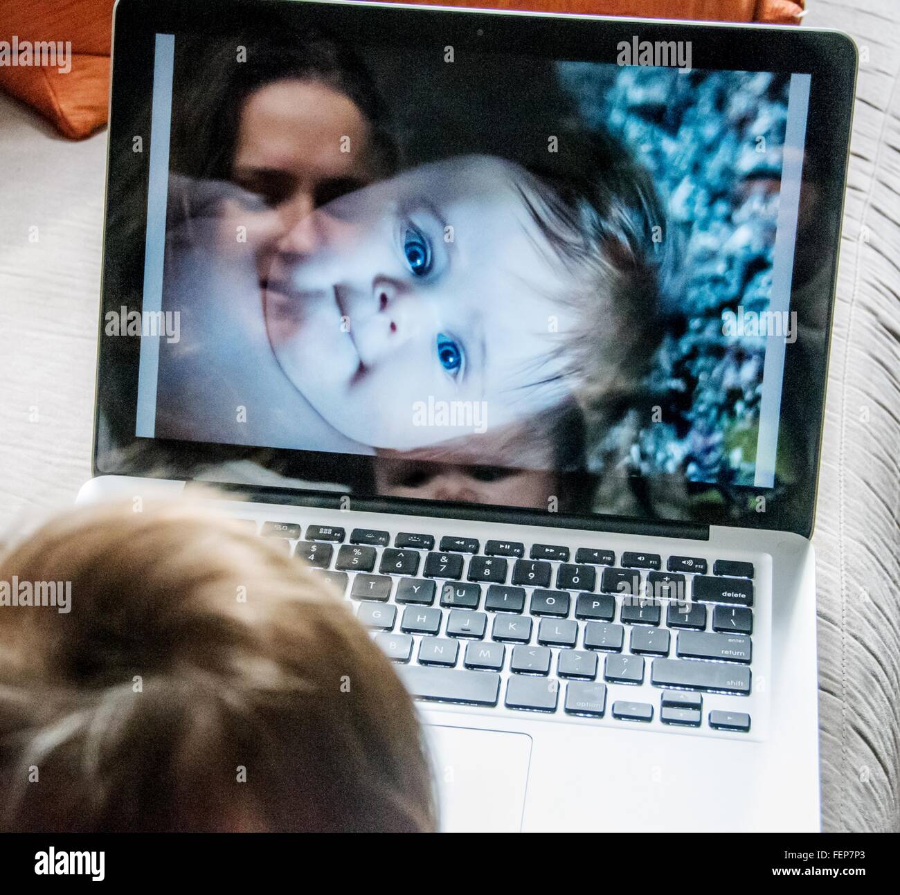 Reflexion der Mutter Blick auf Fotos von Tochter auf laptop Stockfoto