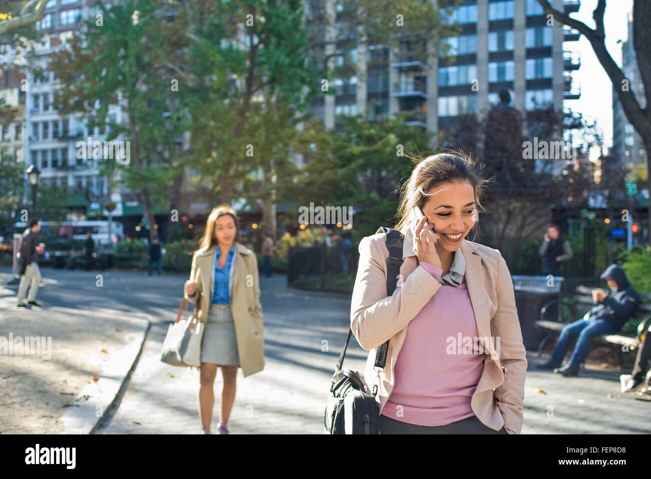 Junge Frau am Smartphone beim gehen durch den Stadtpark Stockfoto