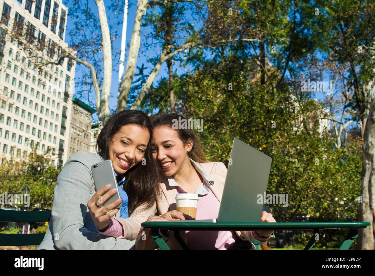 Junge Erwachsene weibliche Zwillinge unter Smartphone Selfie im Stadtpark Stockfoto