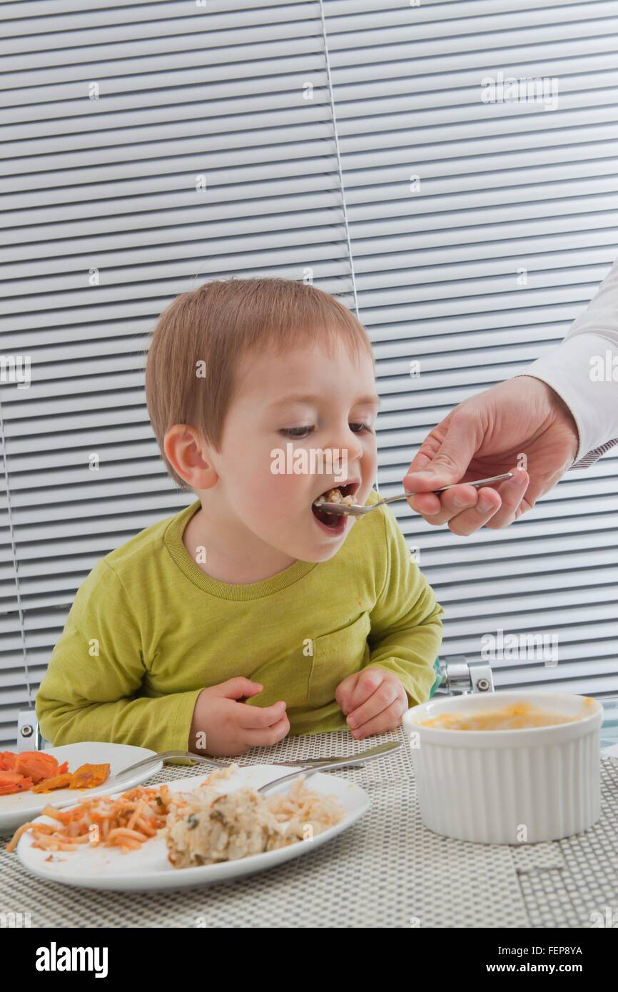 Vater Fütterung Sohn am Esstisch Stockfoto