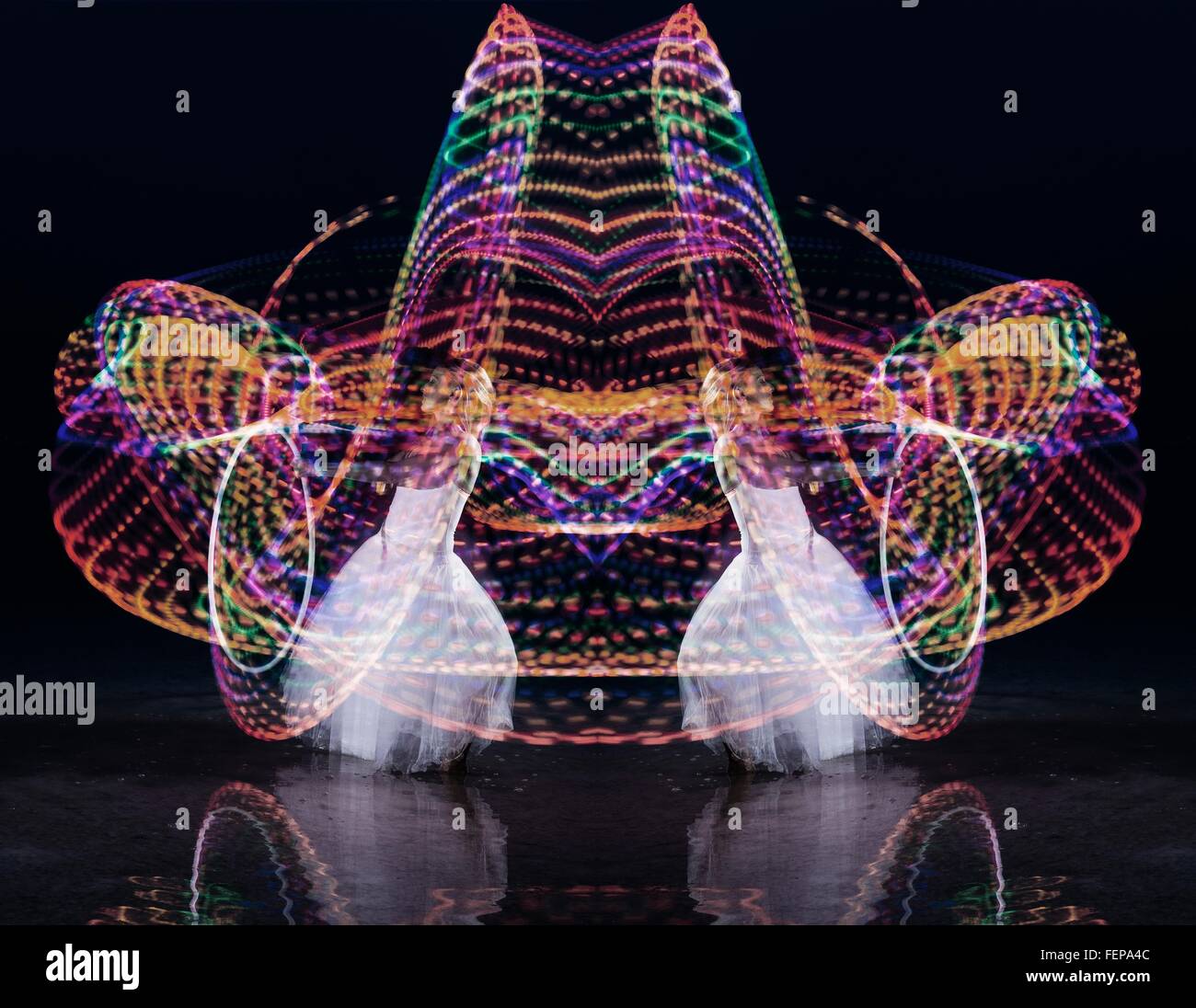 Symmetrische Komposition von Frau tanzt mit Hoop nachts beleuchtet Stockfoto
