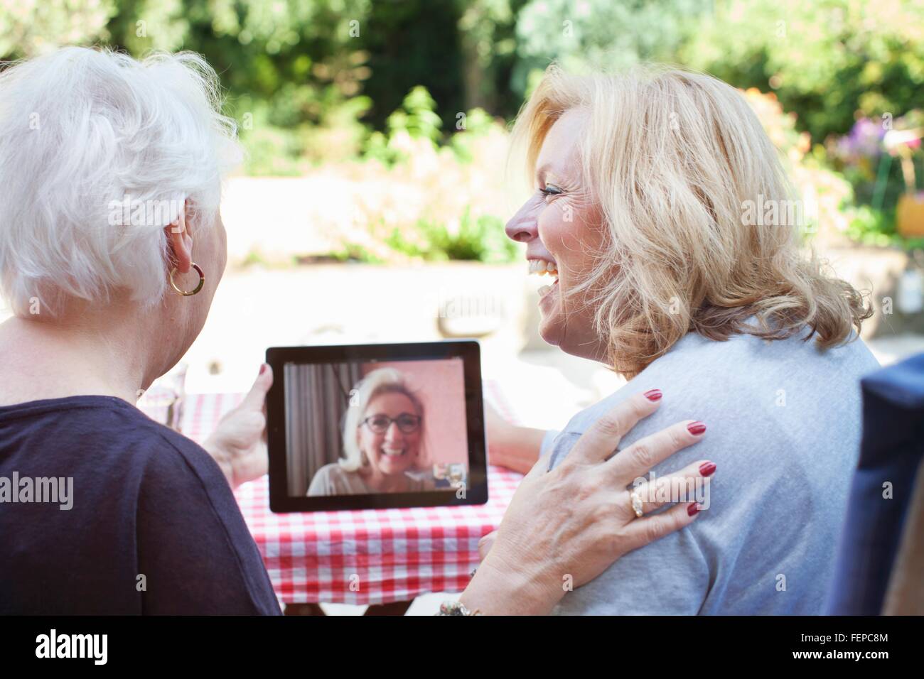 Zwei Frauen sitzen im Freien, digital-Tablette halten, video Gespräch mit Freund Stockfoto