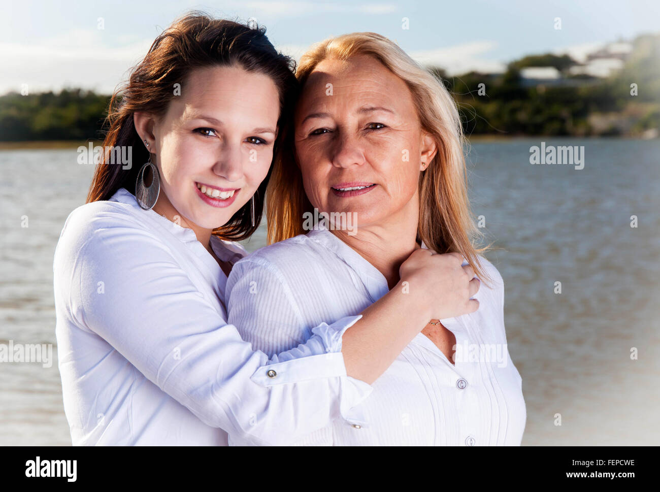 Eine Reife blonde Mutter posiert mit ihrer schönen griechischen aussehende Tochter an den Ufern des Flusses in Südafrika. Ihre Liebe Stockfoto