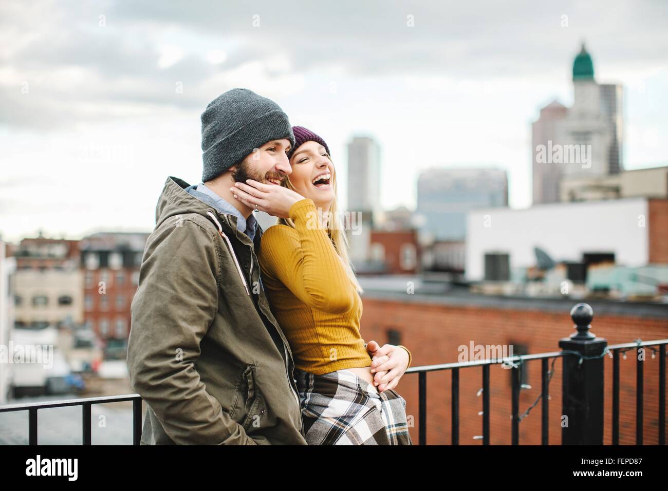 Junges Paar lachend auf Stadt-Dachterrasse Stockfoto