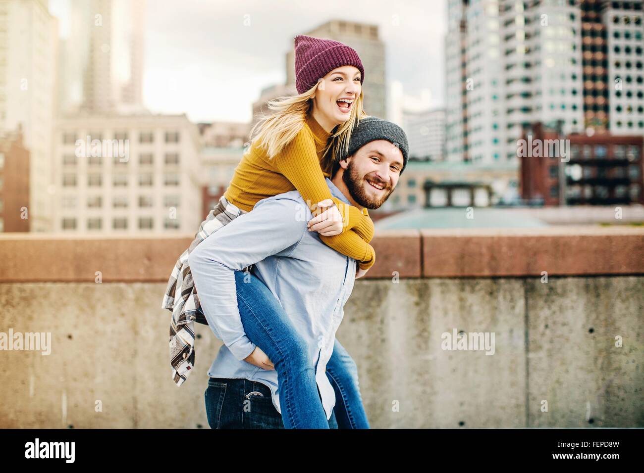 Junger Mann mit Freundin eine Huckepack auf Stadt-Dachterrasse Stockfoto