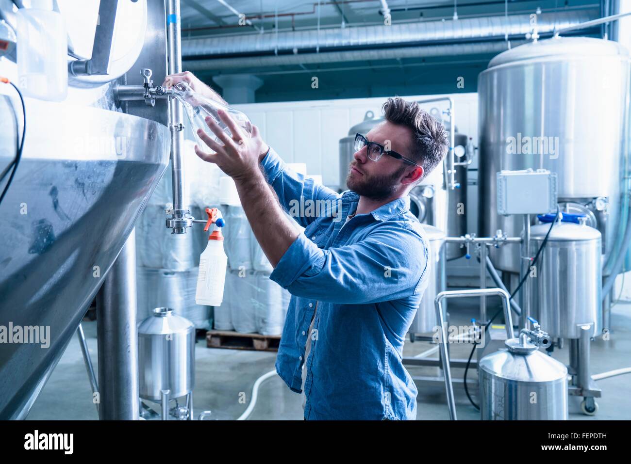 Junger Mann in Brauerei Füllung Kolben mit Bier Stockfoto