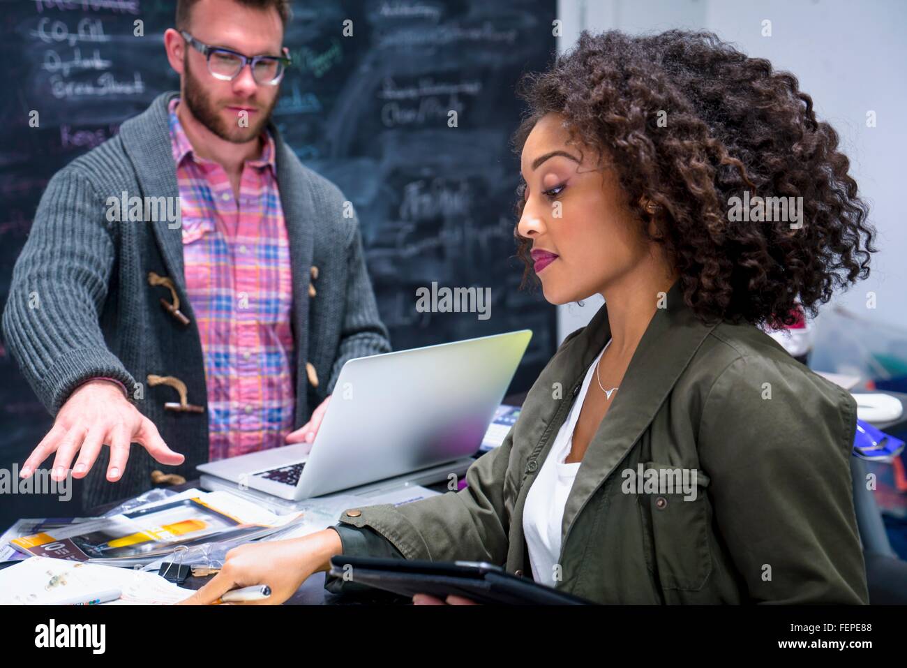 Kolleginnen und Kollegen im Arbeitsplatz über digitale Tablet und Notebook Stockfoto