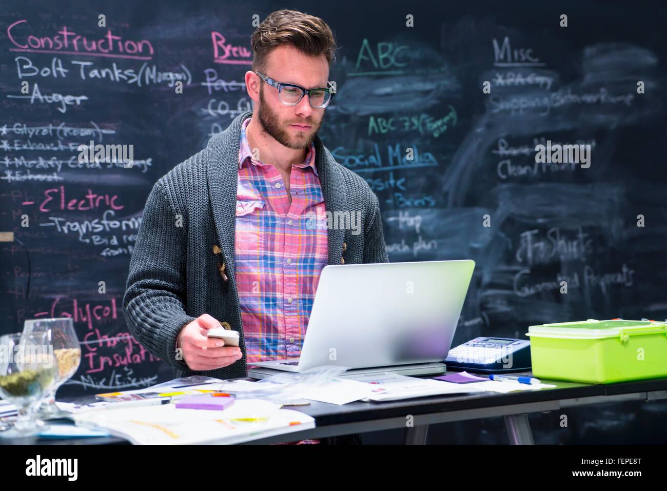 Junger Mann Arbeitsplatz mit Laptop, Smartphone halten Stockfoto