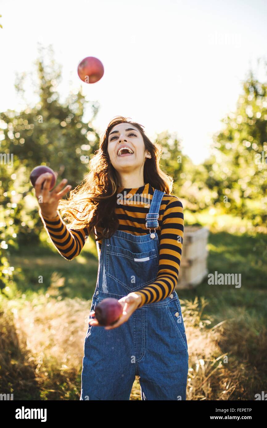 Junge Frau in ländlicher Umgebung, mit Äpfeln jonglieren Stockfoto