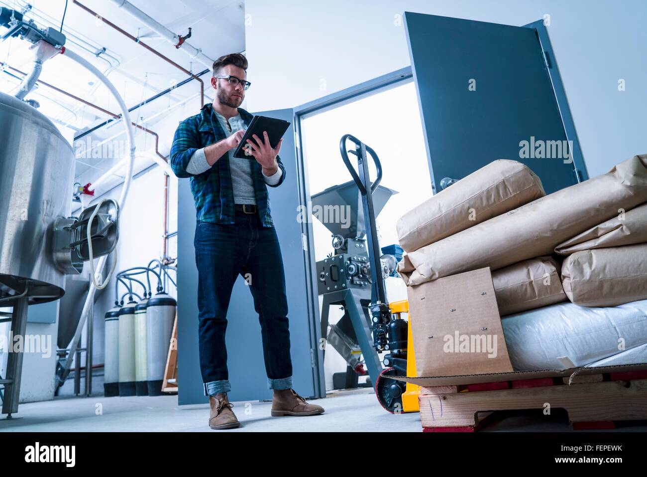 Niedrigen Winkel voller Länge Vorderansicht des Jünglings in Brauerei mit digital-Tablette Stockfoto