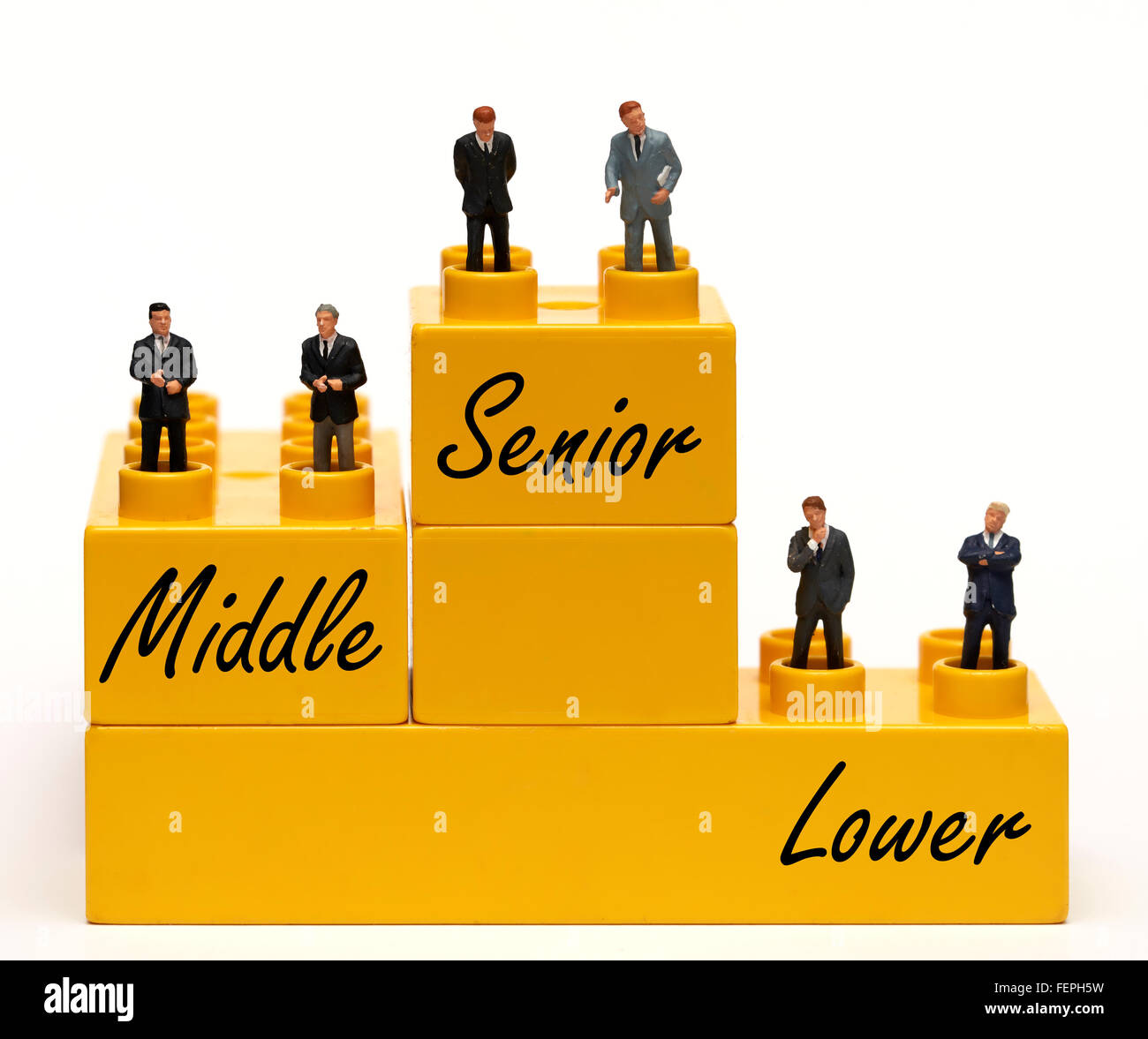 Miniatur Geschäftsleute Figuren gekleidet in Anzügen auf Verriegelung gelb Kunststoff Ziegel Management Konzept Stockfoto