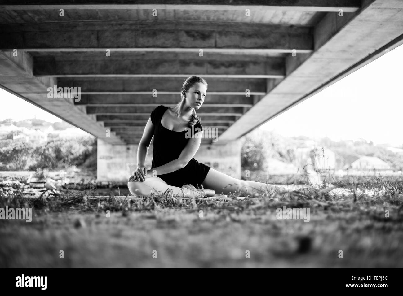 Eine schöne junge Ballerina posiert unter einer Brücke mit dem Fluss hinter ihr viele schöne führenden Linien für bildende Kunst Stockfoto
