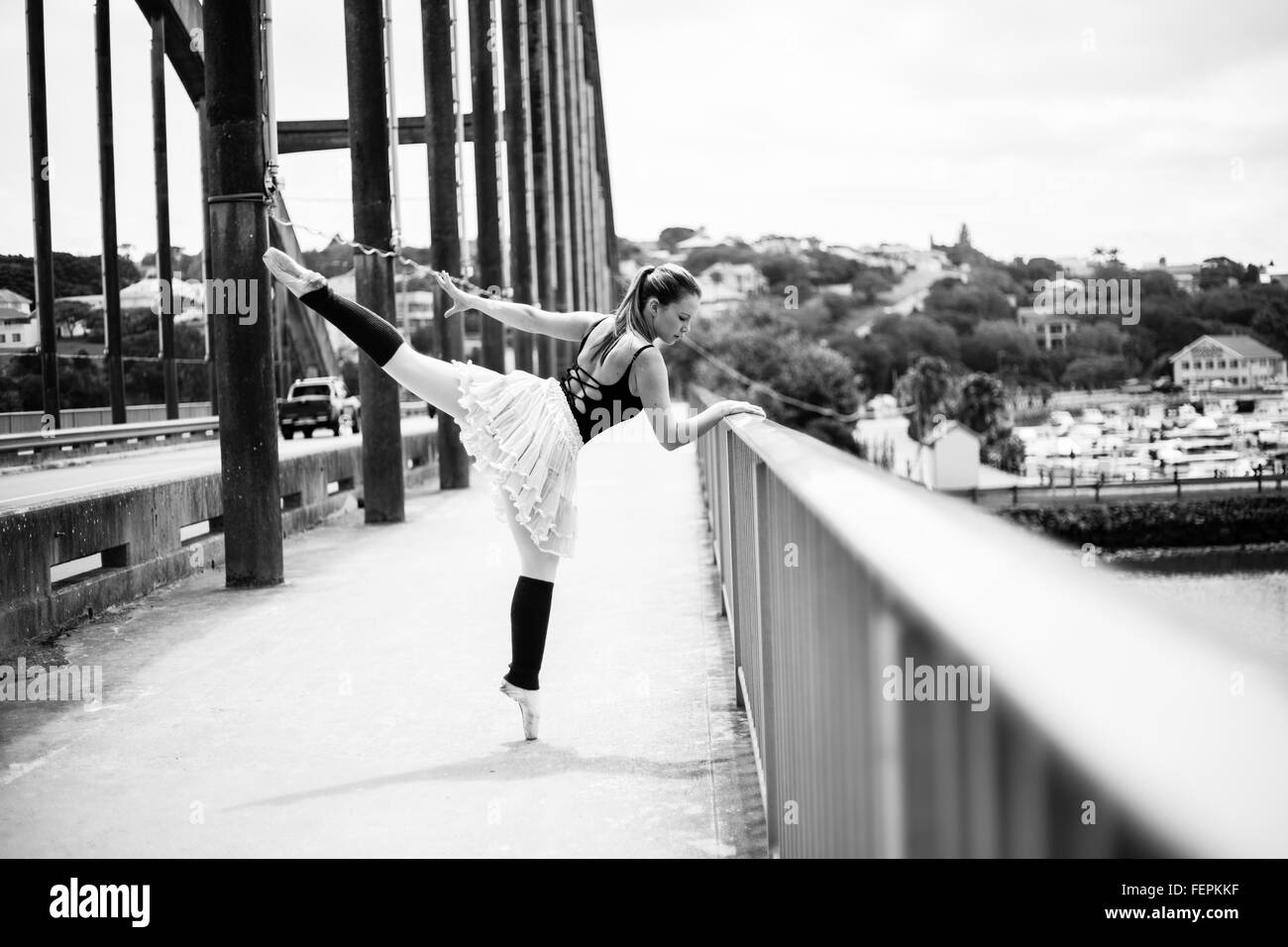 Eine schöne blonde Ballerina ist einen Kick geben, während gegen das Brückengeländer beugte sich über den Fluss. Stockfoto