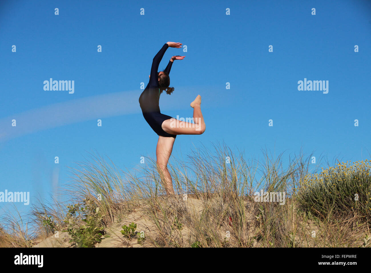 Eine Turnerin tut ihre Routine am Strand in Südafrika. Stockfoto