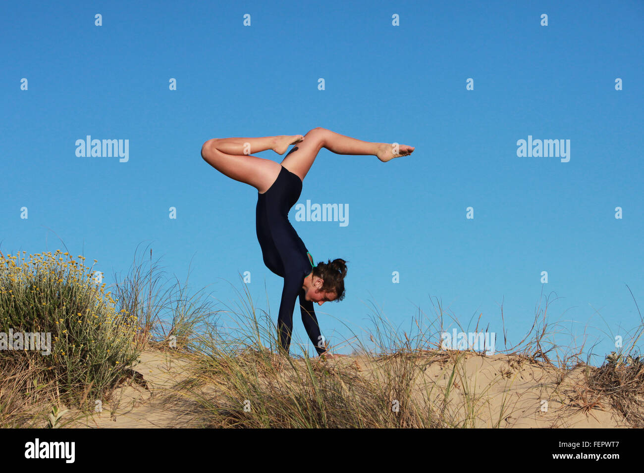 Eine Turnerin tut ihre Routine am Strand in Südafrika. Stockfoto