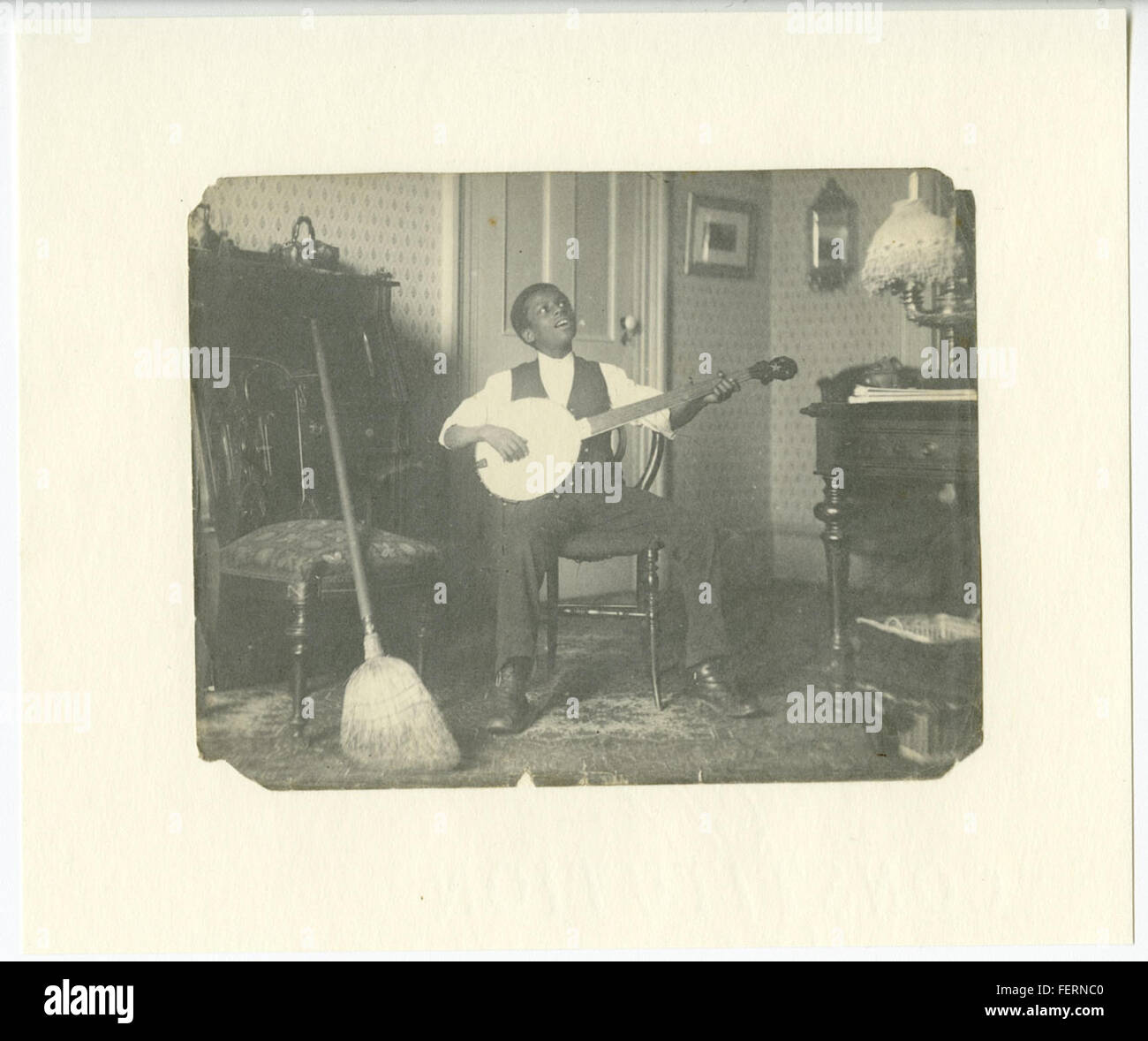 Dieses Bild zeigt eine afroamerikanische Jugend, die das Banjo spielt, ein Schlüsselinstrument in der Entwicklung der amerikanischen Folk- und Bluesmusik. Das Banjo hat eine bedeutende kulturelle Bedeutung in der afroamerikanischen Musiktradition. Stockfoto