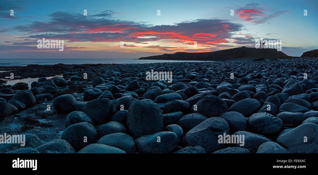 Eine Ansicht in der Morgendämmerung des Dunstanburgh Castle von den Whin Sill-Felsen in den Norden gebracht Stockfoto