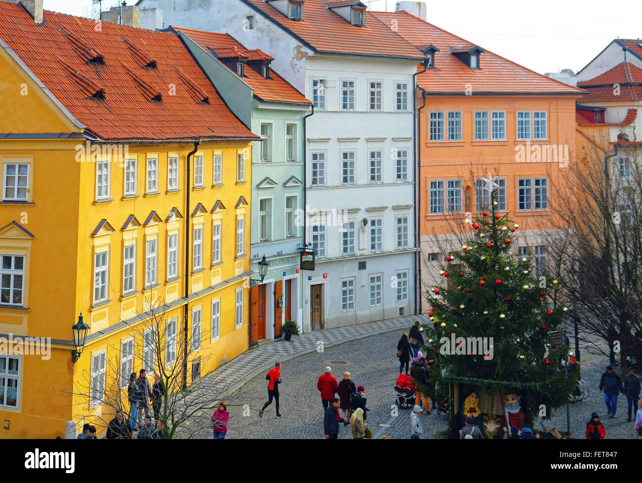 Hellen Apartments in der Straßenszene in Prag an Weihnachten mit gelb, orange und grüne Gebäude und ein Läufer in den Vordergrund Stockfoto