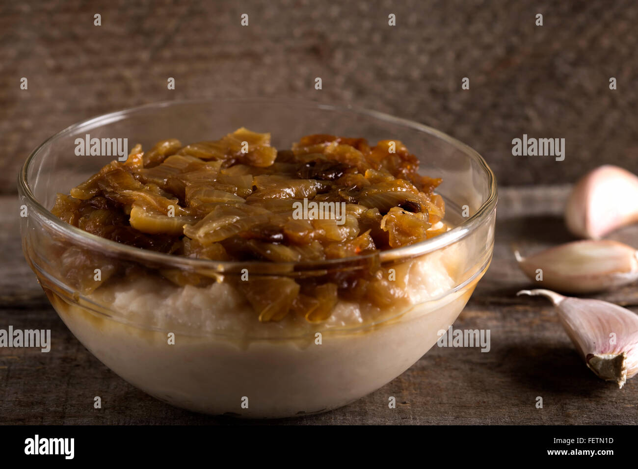 Traditionelles Essen püriert Bohnen "Iahnie" mit gebratenen Zwiebeln obendrauf in transparente Schüssel Stockfoto