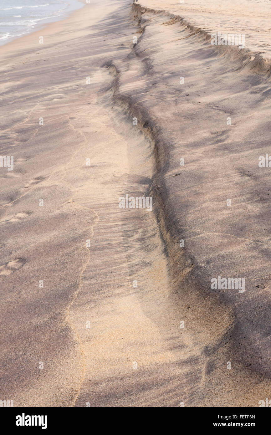 Lila geschwungenen Strand Muster an einem tropischen Strand. Diese bunten Mustern am Strand entstehen durch die Wellen mit Schlamm. Stockfoto