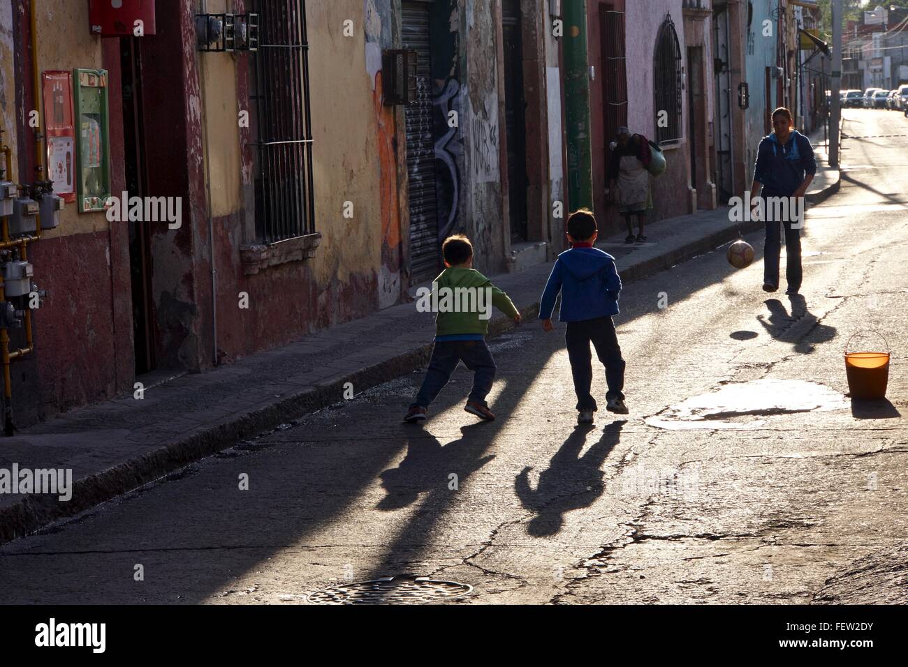 Brüder mit ihrer Mutter auf der Straße Fußball zu spielen. Stockfoto