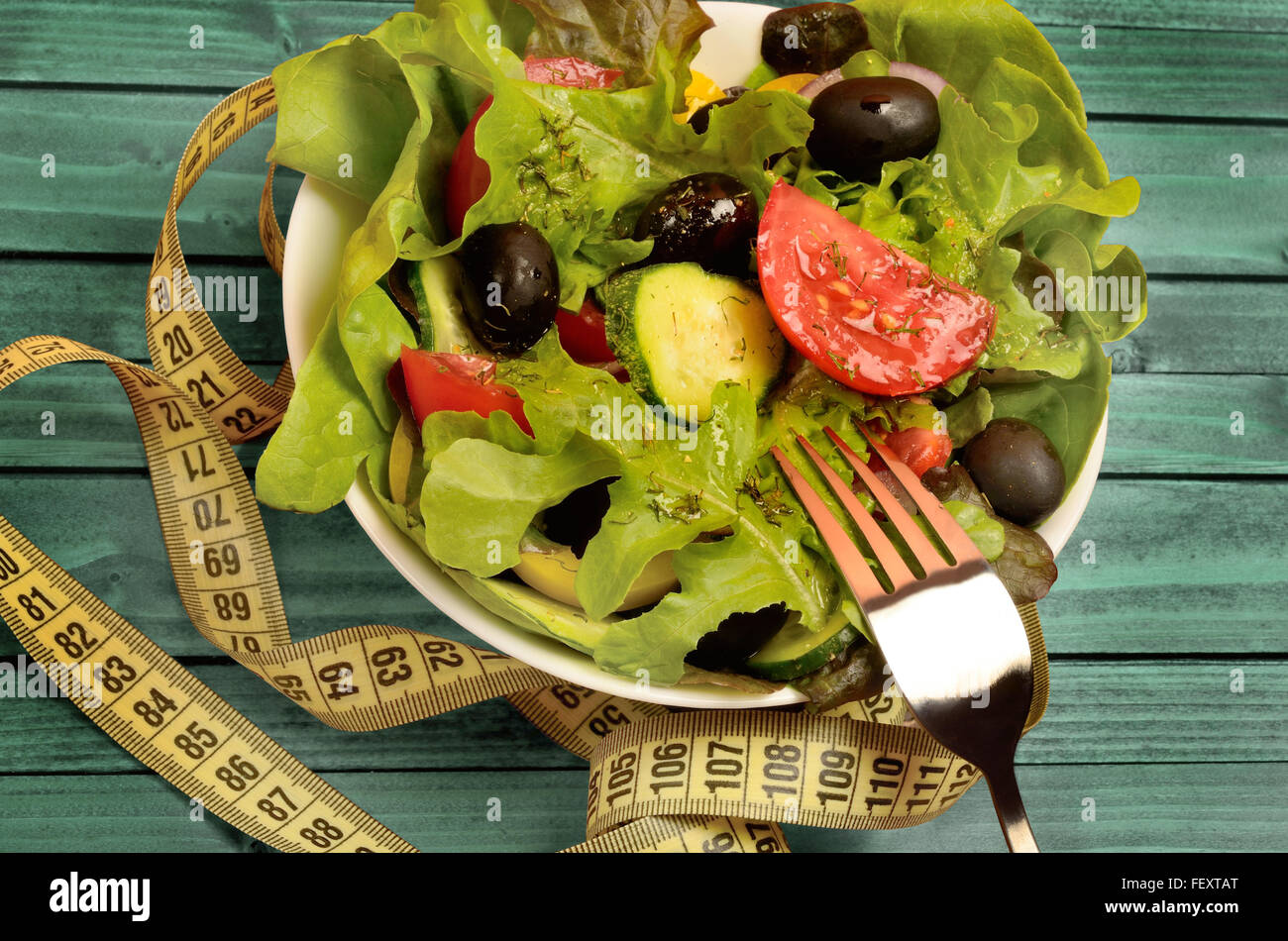 Schale mit Gemüsesalat am grünen Tisch aus Holz Stockfoto