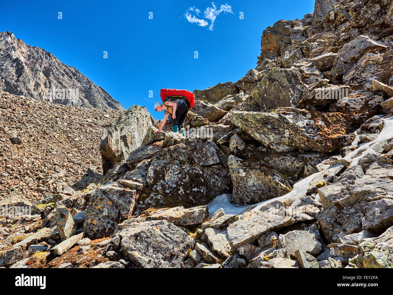Wandern. Frau mit einem Rucksack senkt sich sanft über große Felsbrocken. Berge von Ost-Sibirien Stockfoto