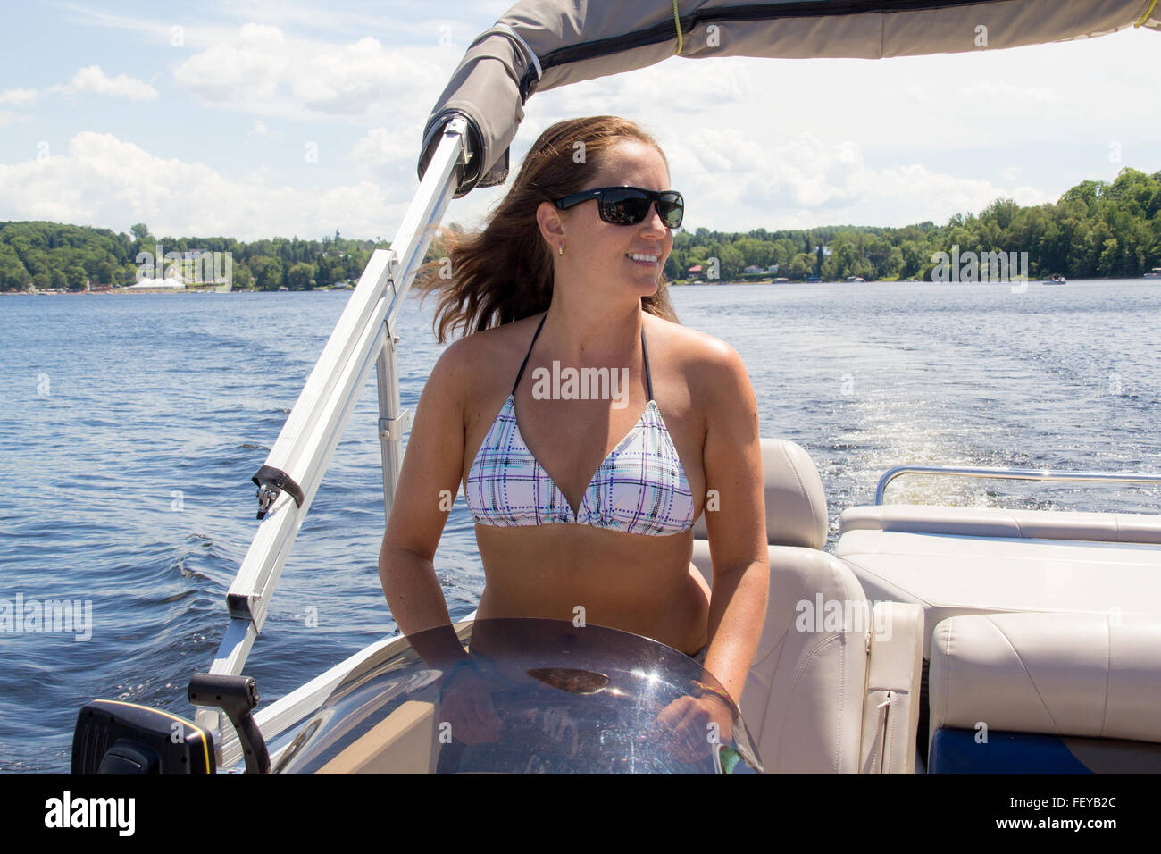Lächelnde Frauen fahren ein Ponton-Boot auf einem See im Sommer Stockfoto