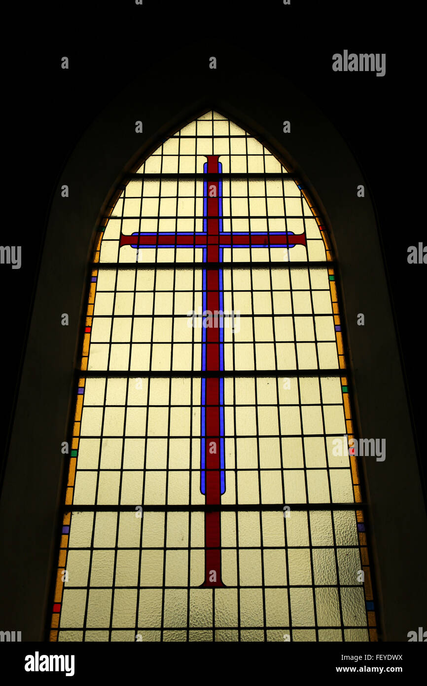 Atmosphärische, dunkel und schönen Fleck Glas Kirchenfenster mit einem Kreuz in Irland Stockfoto